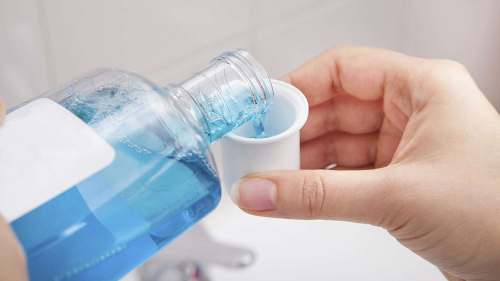pouring mouthwash into the cap to get rid of bad breath
