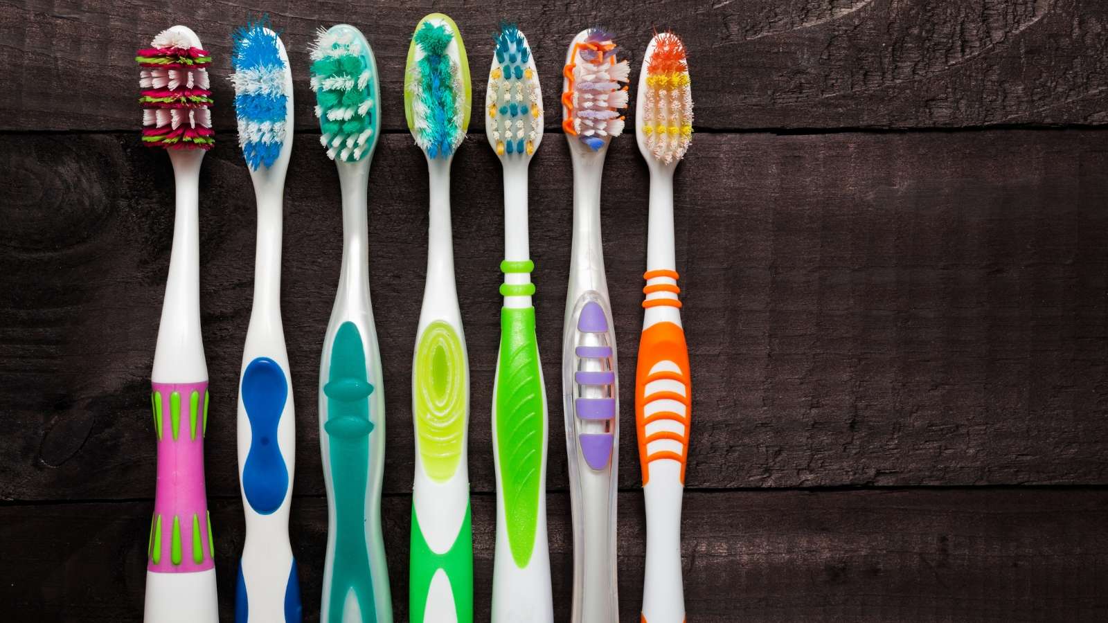 colorful toothbrushes on black wooden background